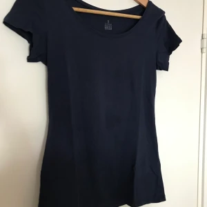 Marinblå T- Shirt organic cotton  - En marinblå T-Shirt med en U ringning. Det finns en fläck på tröjan men den syns så mycket mer på kameran än i verkligheten. Tröjan är i ekologisk bomull.