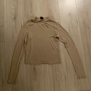Beige topp - En beige topp från Gina tricot, lite högre i halsen storlek S.