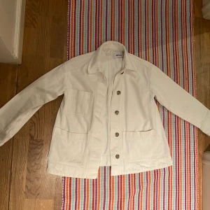 VIT TUNNARE JACKA FRÅN WEEKDAY - Jättesnygg och simpel tunn jacka från WEEKDAY, jättelätt att tvätta. Tre fickor och knappar ifall man vill stänga den. 200kr 