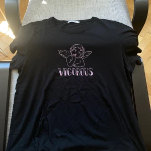 T-shirt med ängel - Fin t-shirt i nyskick med tryck av en ängel. Storlek L. Frakt tillkommer om den ska skickas. 