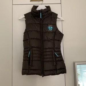 Väst från Equestrian style, Covalliero - Mörkgrön/kaki färgad ”rid/stall” väst från Equestrian style med hög krage. Strl 36 använd ca 3 ggr och delft i väldigt bra skick. Fraktas eller möts upp i norrort/sthlm stad.