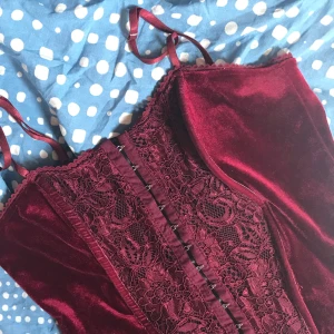 Röd samets topp - Mörk röd korsett liknande topp med knäppen💕.         Frakt tillkommer på 40kr!!