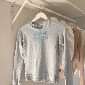Ljusblå North Sails collegetröja  - Superfin collegetröja från North Sails med en liten v-ringning i halsen! Tröjan ska vara lite sliten i sig själv, men annars är den i väldigt bra skick! Använd ett fåtal gånger.