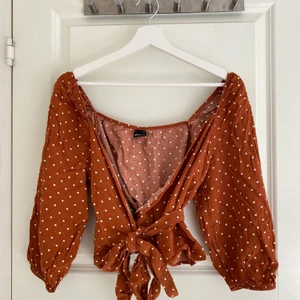 Prickig omlotttopp - Brun omlottopp med vita prickar och knyte i midjan. Är i en stor storlek men passar mig som vanligtvis har stl 36.