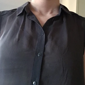  - Grå blus i tunn polyester. Rak, vid passform. Ärmlös med knappar fram och liten krage. Längre bak än fram. 

Jag skickar med posten eller möter upp i Stockholm. Betalning via Plick, kontoinbetalning, kontant eller swish.

