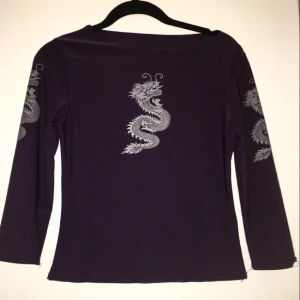  - 00-tals inspirerad lila tröja med drakar på framsidan samt sidorna av ärmarna. Tröjan sitter tajt men är stretchy så passar de flesta storlekarna mellan S-M! 