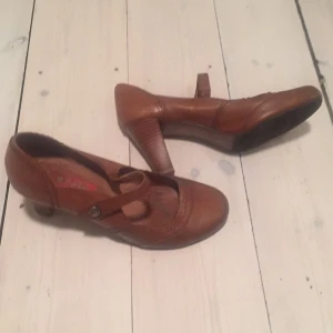  - Bruna läderpumps med rem och fina detaljer. Något slitna i sulan med ser bra ut på. DM hög klack