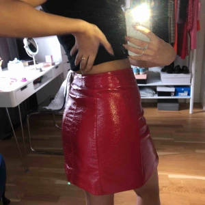  - Röd lackad kjol i skinn imitation. Skicket är som nytt! Strl XS men passat definitivt en S. Köparen står för frakt!