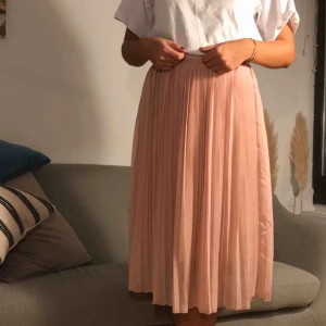  - Ljusrosa plisserad halvlång kjol. Frakt tillkommer