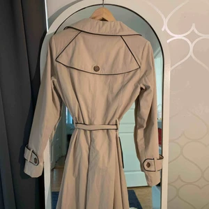  - En jättefin trenchcoat i färgen beige. Har en liten fläck och sen en halv knapp som är av vid ärmen. Inköpt för 1000kr.   +frakt 