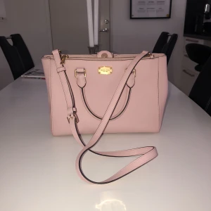  - Ljusrosa väska från Michael Kors, en lång axelrem och två mindre handtag. Det långa är avtagbart. Sista bilden visar en liten fläck som finns på baksidan av väskan. Använd ca 2 gånger, och är nästan som ny!