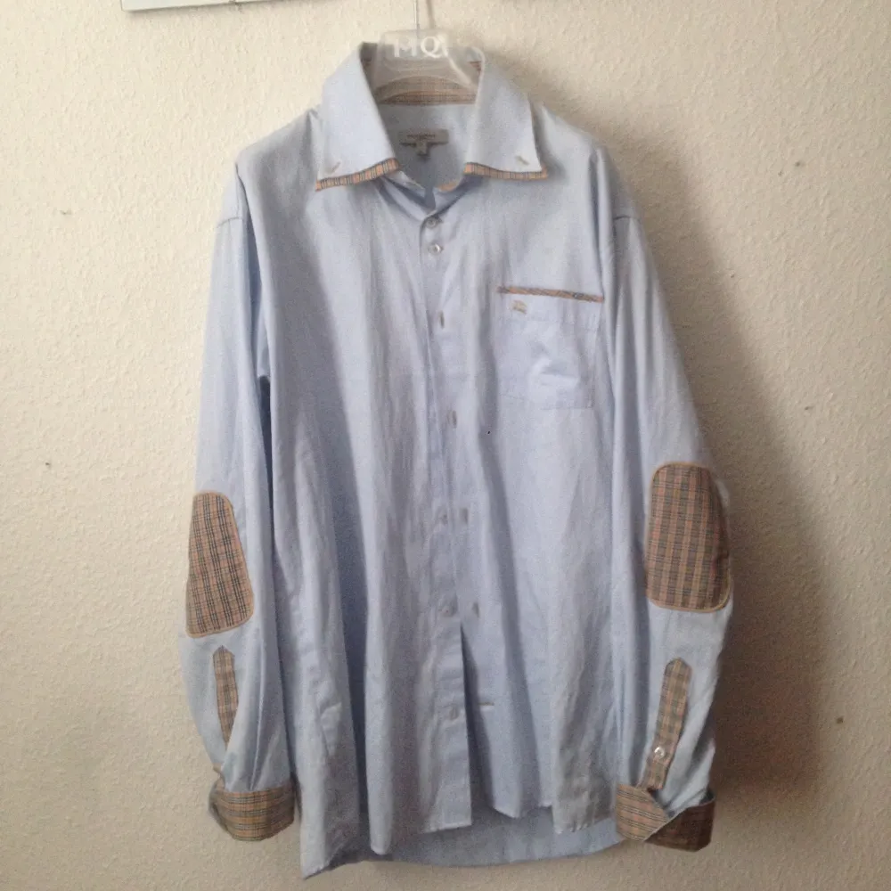 Burberry skjorta. Denna skjorta är äkta, den har en insydd dubbelkrage med burberry mönster på. Armbågslappar med mönster och uppvikta ärmar med mönster på. Priset kan sänkas.. Skjortor.