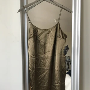  - Säljer denna tuffa midiklänning i shimmer-khaki  pga den var för liten. Aldrig använd och tags är kvar! Köpare står för frakt!