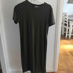  - En militärgrön, ribbad topp som har slits på vardera sida. Den är knappt använd och i bra skick!