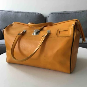  - VINTAGE DOKTORSVÄSKA/KAPPSÄCK  Pippiväska i gul skinnimitation. Fint skick med mindre slitage. Sömmen på ena remmen har släppt lite (se bild) med det är lätt fixat med nål och tråd.  Mått: 44(längd)x25(bredd)x30(höjd)  Köparen står för frakt.