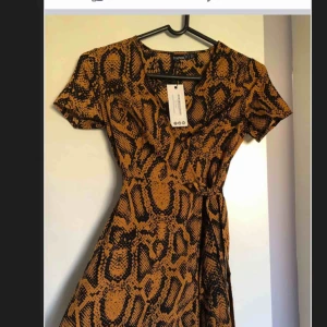 - Skitsnygg omlottklänning med ormmönster i strl 34 oanvänd med tags kvar.