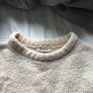  - En lurvig tröja, ganska kort och den är beige.