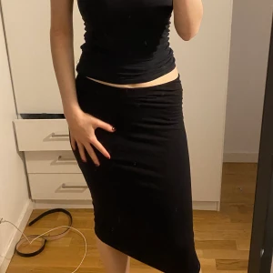 Svart kjol - En tight tyg kjol som går ner till knäna. 