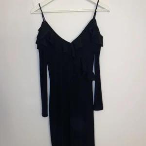 Svart klänning  - Svart klänning från Gina i strl Xs🖤 använd 3-4 gånger , volanger på fram och baksida samt smala band över axlarna , sitter tight men är stretchig med luftigt material! Säljs för 50kr + frakt 🖤