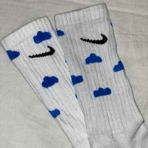 Nike cloud sock  - Höga Nike strumpor med blåa små moln på, helt oanvända. Supersnygga att matcha med en blå outfit tex. ❤️  (de är hemmagjorda med textilpenna, så det kan kanske vara lite ojämnt här o där, men jag personligen tycker de blev rätt bra) Nike loggan är INTE ditmålad