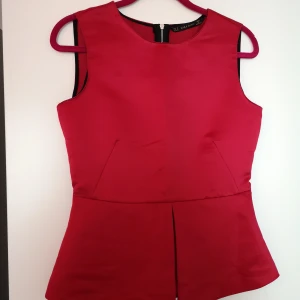 Peplumtop från Zara - Peplumtop i tjockare satin med grövre dragkedja i ryggen. Färgen är inte lika klarröd som på bilden, lite dovare mot vinrött. 