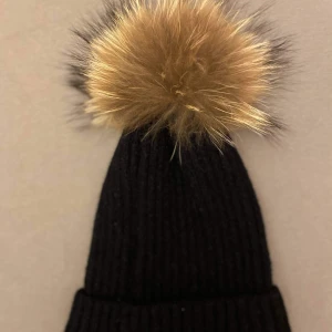 Svart tofsluva äkta päls  - En svart tofsluva med tofs i äkta päls, som ny! Tofsen är avtagbar så att mössan kan tvättas separat. Enbart provad, så i nyskick :) Mössan kan hämtas i Alingsås eller skickas per post, postar samma dag som betalningen finns på kontot :) 