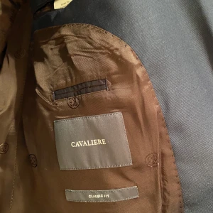 Cavaliere mörkblå kostym säljes - Inköpt på Noelle i Kalmar för 4999.  Kavajen är i storlek 60 och Classic Fit. Byxorna storlek 58.  Enbart använd en gång och därefter inhängd i sitt fodral som medföljer vid köp.  https://www.cavaliere.se/herr/kostym/mixandmatch/jkt-parker-1