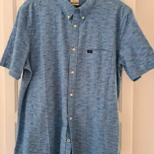 Modell kortärmad blå skjorta av märket LEE. Strl L. Aldrig använd. Köparen står för frakt.