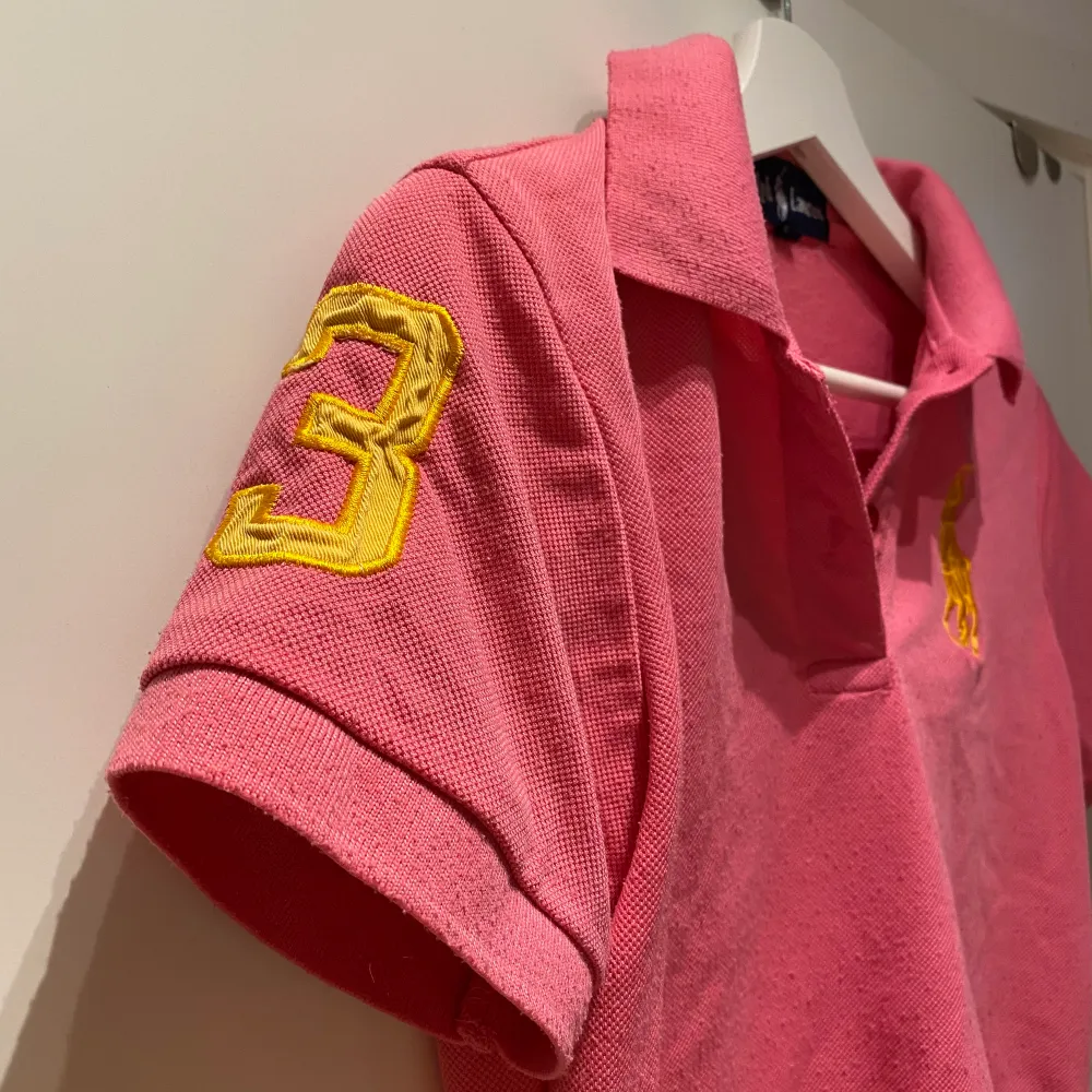 Rosa Ralph Lauren T-shirt. Köpt begagnad, tvivlar på att den är äkta, men det är väldigt bra kvalite och detaljerad för att vara en kopia isåfall. Säljer för att den sitter för tajt i armhålan på mig. . T-shirts.