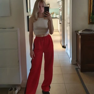 Byxor  - Röda lösa byxor med svarta ränder på sidan och öppningsbara knappar. Ganska långa på mig som är 165 cm. (Har justerat byxorna så de ska se ut som de gör när de passar. De är alltså för stora för mig egentligen) Frakt tillkommer, kan även mötas upp i Stockholm.