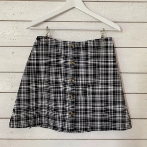 Svartvit rutig kjol, Monki - Kjol som knäpps i fram med knappar, slät baktill. Använd men i fint skick. Skön passform och passar mig som vanligtvis har storlek S. Frakt tillkommer (42kr). 