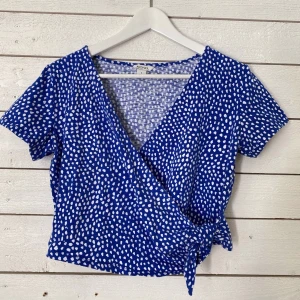 Wrap blouse, Monki - Blå och vit prickig wrap blouse. Använd men i fint skick. Frakt tillkommer (42kr). 
