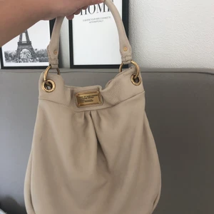 Marc By Marc Jacobs väska - ✨Säljer denna beige/krämvita sparsamt använda Marc By Marc Jacobs hand/axelremsväska med gulddetaljer. Mycket små defender, men inget man lägger märke till. Pris kan diskuteras, köparen står för frakten!✨ (Har inget kvitto, då jag fått den av familjemedlem) 