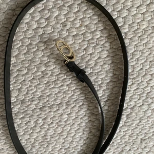 Svart skärp med guldringar (ej äkta)  - Svart skräp med två ihopsättande guldringar (ej äkta) från KappAhl. 115cm/120cm, vet ej vilket av dem två pga av att jag har klippt bort lappen. Har gjort några extra hål hos skomakare pga att det var förstort för mig. Använd endast två gånger. Köparen står för frakt