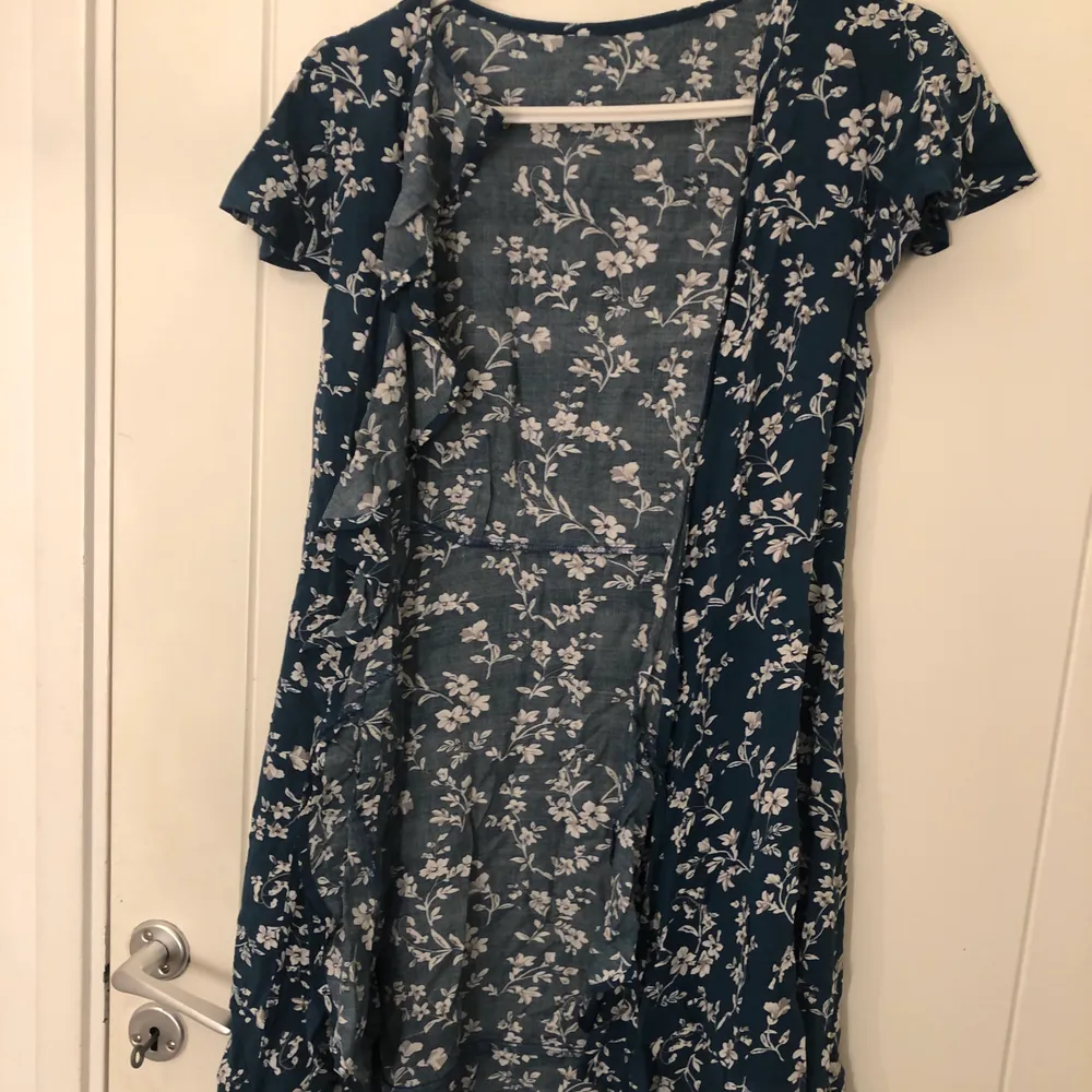 En marinblå klänning med vita blommor på, ej använd, stl L, en knytklänning . Klänningar.