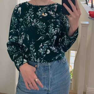  - Jättefin och skön blus med fin öppning på ryggen. Mönstret har jättefina färger  (syns mest på bild 3). Den är tunt o skönt material, funkar på sommar och vinter. Lite båtringad i halsen. Jättebra skick!!! Frakt tillkommer