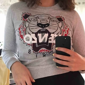 Kenzo tröja - Grå Kenzo tröja med rött tryck. Använd endast ett fåtal gånger och säljs då den inte kommer till användning och hoppas att den kan användas av någon annan! Tröjan är i storlek M men passar även superbra på en person som är i storlek S!❤️ Nypris 1800kr