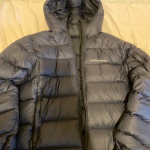 Peak Performance Jacket - Blå Peak Performance jacka (MEN) strl S men stor i storleken passar även M. Köpt från SkiTotal för 3800kr. Värmeskala 4/4, Avtagbar huva, Full zip, Fickor i sidorna. Material: 100% Polyamid, 90% Dun och 10% Fjäder. INGA BYTEN. 2200 kr