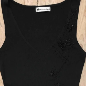 Svart märkes top - Svart ribbat linne med broderier.  Red Month jiaozi  XS 