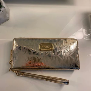 Äkta Michael Kors plånbok  - Galet snygg guld glansig Michael Kors plånbok. Nyskick, inga skråmor osv, knappt använd. Får plats med ca 20 kort. ORGINALPRIS: 1100 kr