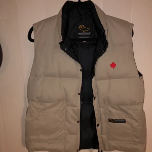 Canasta Goose väst i Stl XS. Fint skick! - En grå/beige Canada Goose väst i stl XS (passar även S). Knappt använd så den är i toppskick. Nypris ca 4500kr. Finns i Stockholm eller köparen betalar frakt. 