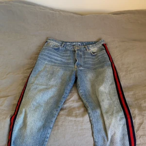 Jeans med ränder  - Blåa jeans (never denim) från BikBok med röda och marinblå ränder på vardera sida. Jeansen är använda ett par gånger och är i hyfsat bra skick. En liten slitning har uppståt på höger ficka men ingenting som stör. Köparen står för frakten🤍