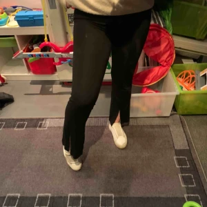  - Ett par svarta byxor med slits ner till, från Gina tricot. Byxorna har en liten fläck upptill men inga andra defekter. Passar en lite kortare person från 150-160 cm. Köparen står för frakt
