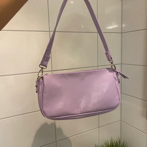 Lila baguette bah  - Liten axelremsväska som saknar dragkedjans stopp men går att laga. 