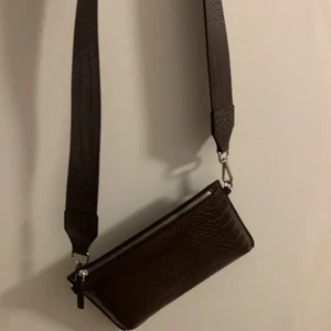 Brun konstläder väska ifrån Carin Wester  - En helt oanvänd väska i brun fake läder tyg ifrån Carin Wester. Bandet ingår till väskan 