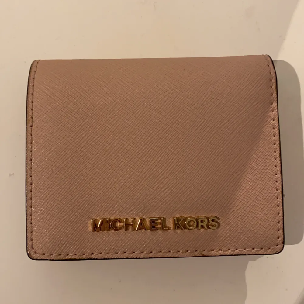 Jättefin äkta Michael kors plånbok! Den är i perfekt skick då den används väldigt lite varför jag också säljer den. Praktisk, rymmer väldigt många kort och kontanter! Den är jättefin färg rosa/beige. Köppte den för runt 6/700 kronor tror jag. 💕Men högsta bud får den!💕 minst 200kr  . Accessoarer.