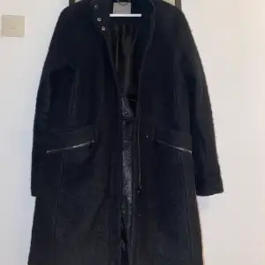 En rak svart kappa från VeroModa. Använd en höst/vinter. Försluts med en dragkedja och har två fickor. Storlek S