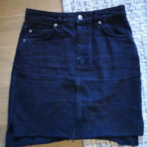  - Mörkgrå jeanskjol i tight modell. Kjolen har en liten slits vid sidorna och den är lite längre bak än framtill se bild 3. Hämtas i Årsta 