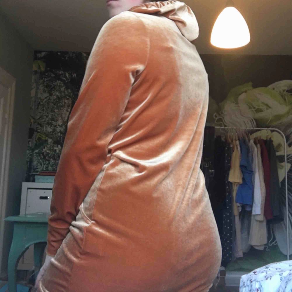 Cool rostbrun sammetsklänning med luva och stor ficka fram. Passar perfekt i längd för mig som är 160 men kan även användas av längre beroende på var man vill att den ska sluta. Köparen betalar frakt, annars möts vi upp i Lund.. Klänningar.