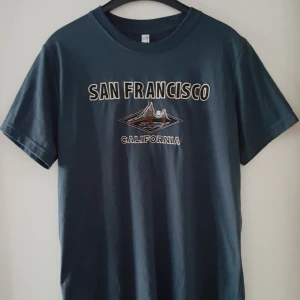  - Vintage mörkgrå t-shirt i storlek M. Fraktkostnad blir 36kr.